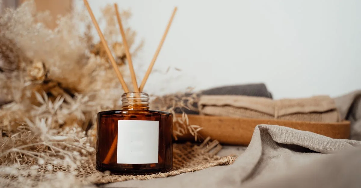 Présentation cozy à la maison avec un diffuseur en verre ambré et des bâtonnets d'encens, dégageant de la tranquillité.