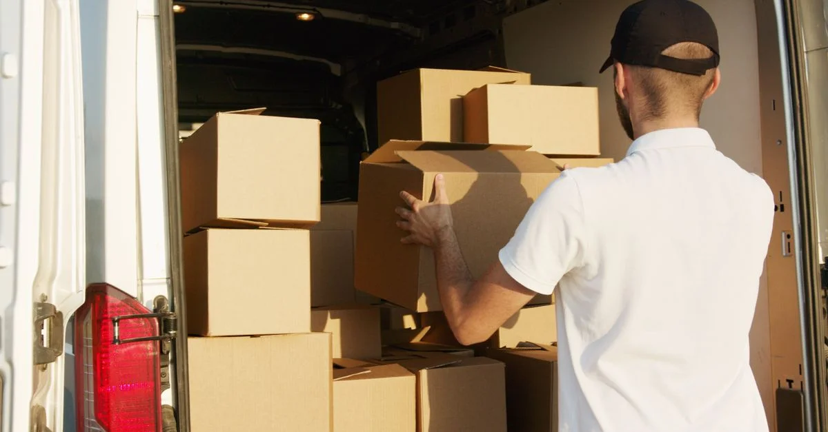 Livreur organisant des cartons dans une camionnette de livraison pendant la journée.