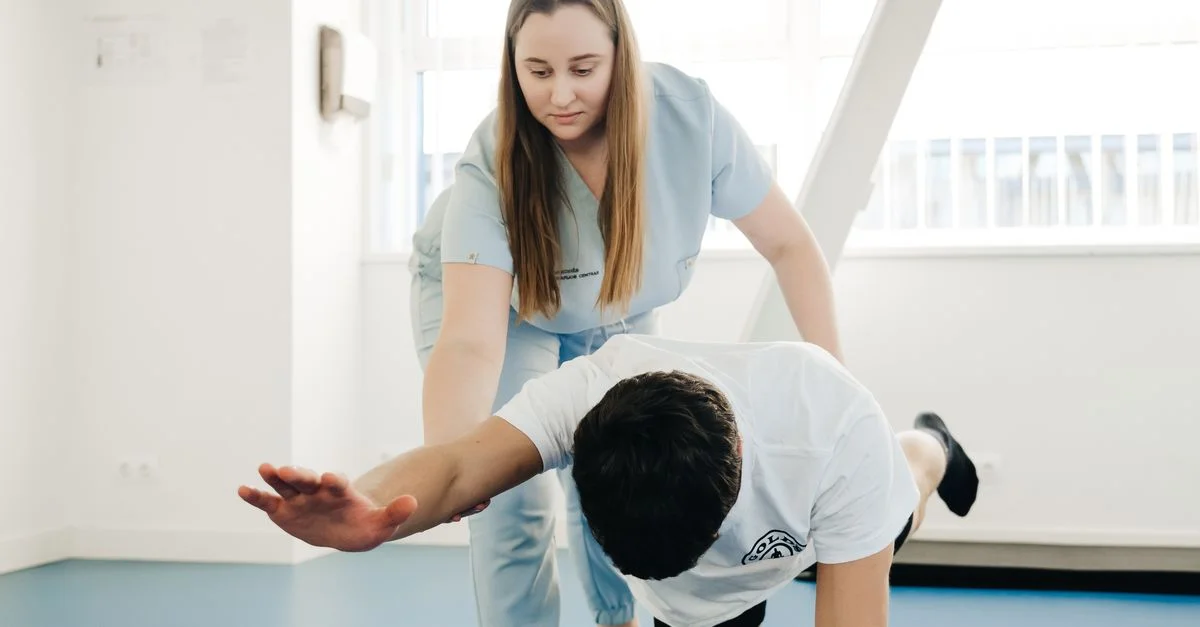 Un kinésithérapeute aide un patient à faire des exercices d'étirement à l'intérieur.