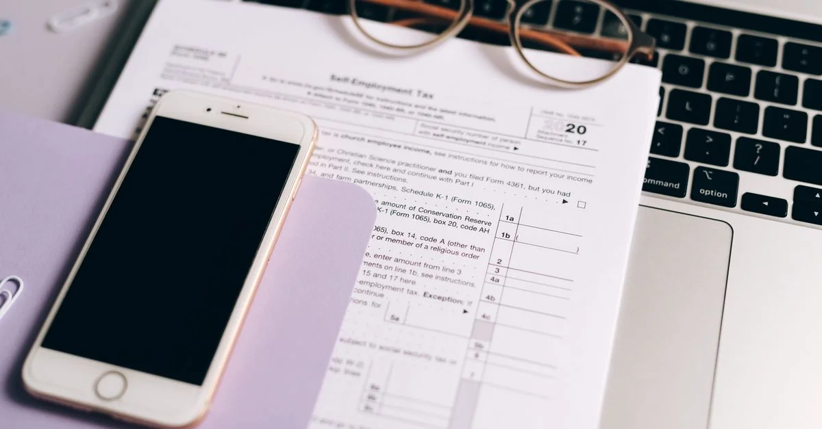 Gros plan sur des documents fiscaux avec un ordinateur portable et un smartphone sur un bureau.