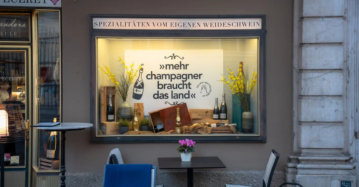 Charmante vitrine de magasin à Salzbourg avec du champagne et des fleurs.