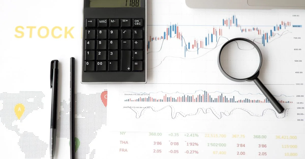 Vue de dessus des outils d'analyse du marché boursier incluant calculatrice, graphiques et loupe.