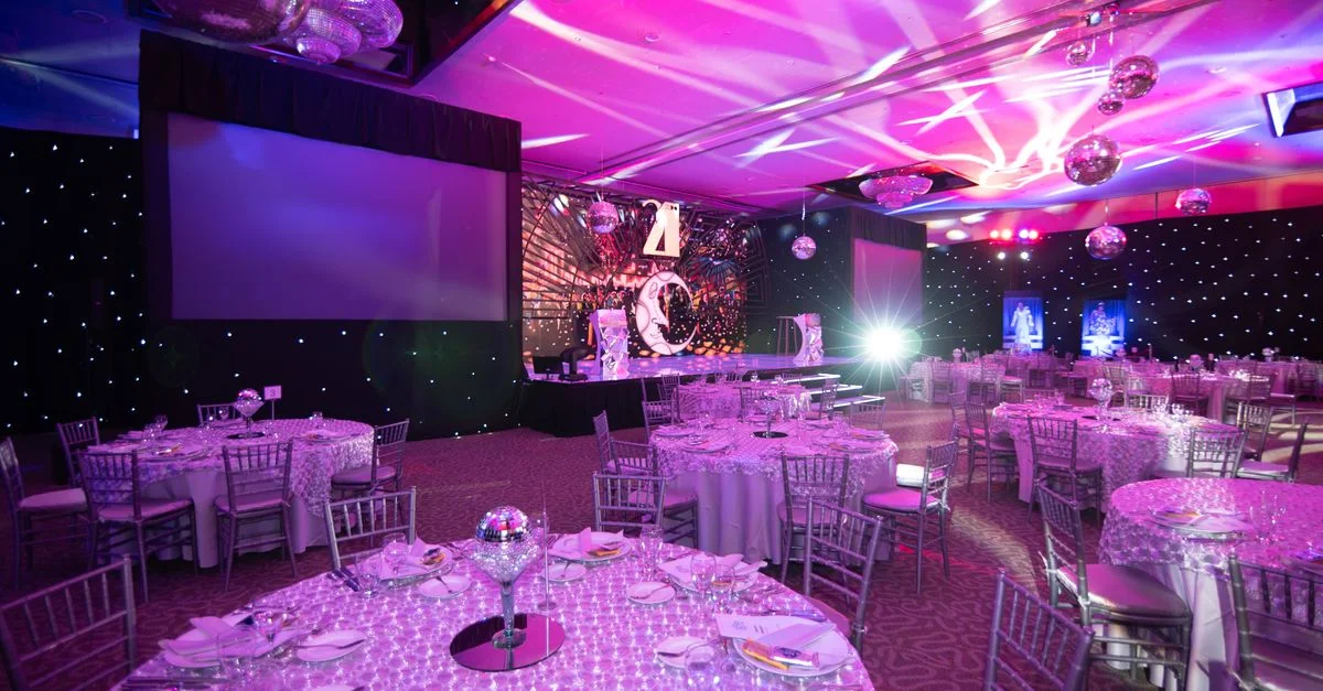 Configuration de dîner élégante dans une salle d'événements luxueuse avec un éclairage ambiant et des boules à facettes.