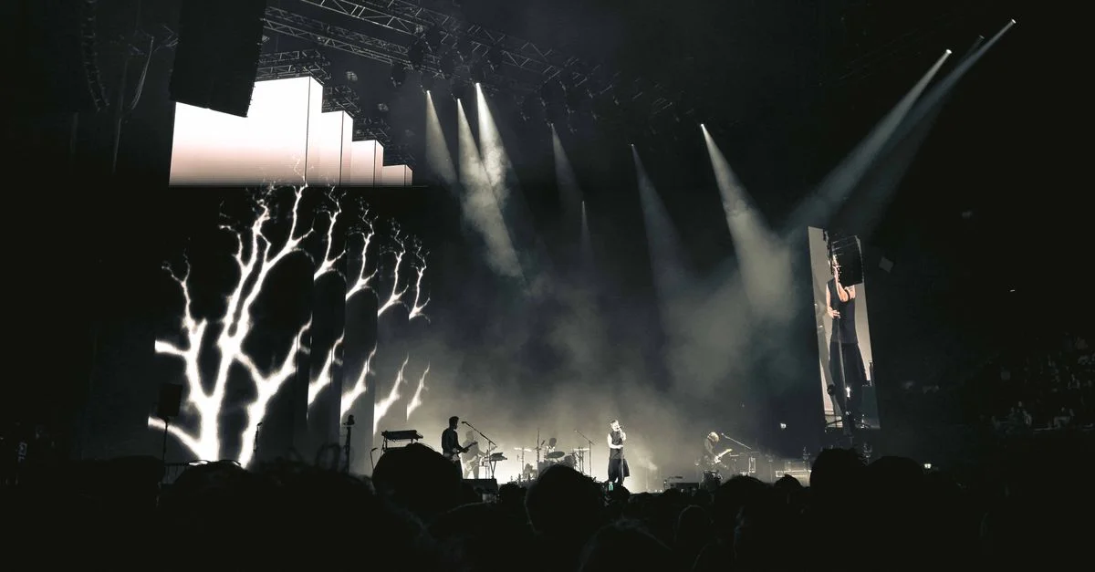 Concert nocturne captivant avec lumières, fumée et public à Amsterdam.