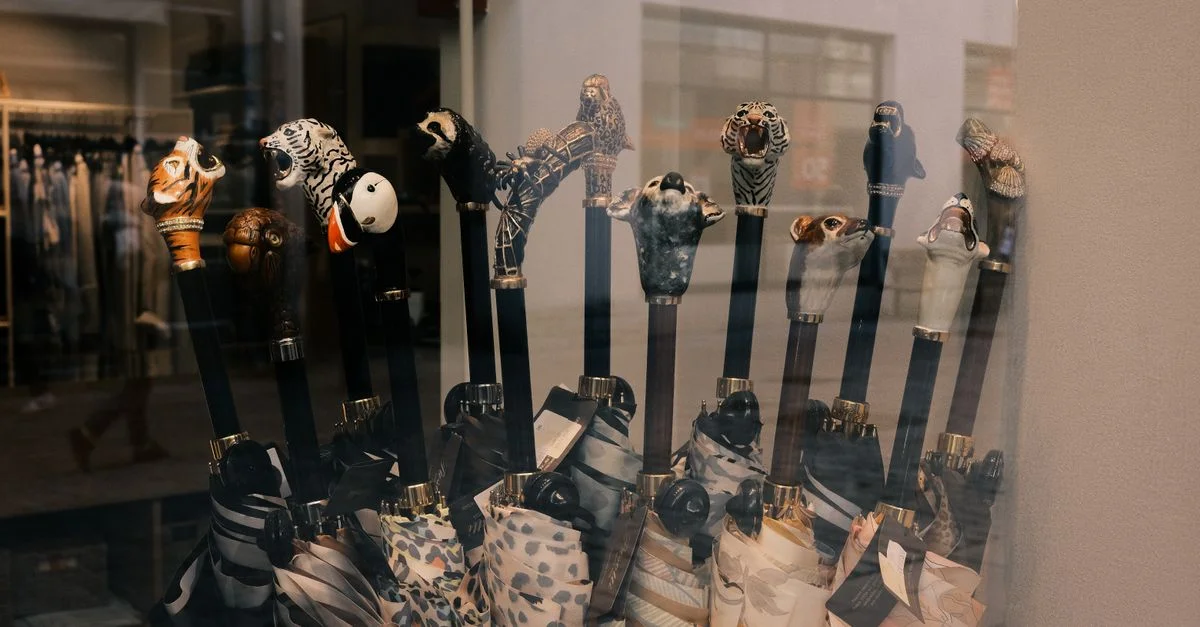 Des parapluies à poignée en forme d'animaux, aux designs et couleurs variés, sont présentés en vitrine.